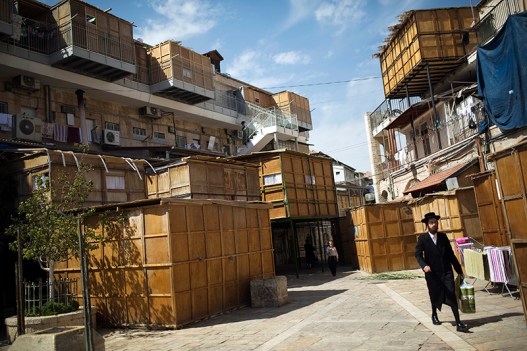 Ultra-Orthodox Jewish men walk near ritual booths, known as sukkot, in Jerusalem's Mea Shearim neighbourhood